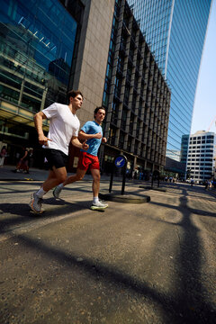 Men jog side by side on a street in downtown London