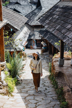 Woman Walking Along Stone Street in Traditional Wooden Village