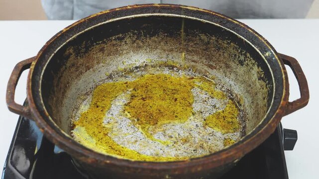 Vegetable oil is poured into a deep cast-iron frying pan. Medium shot.