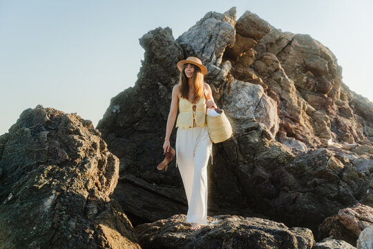 Stunning woman makes her way through the rugged shoreline.