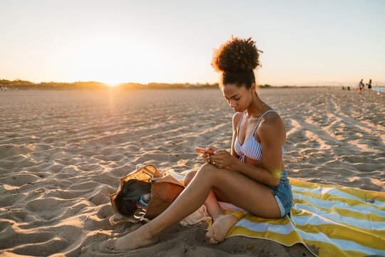 Woman using smartphone on beach at sunset