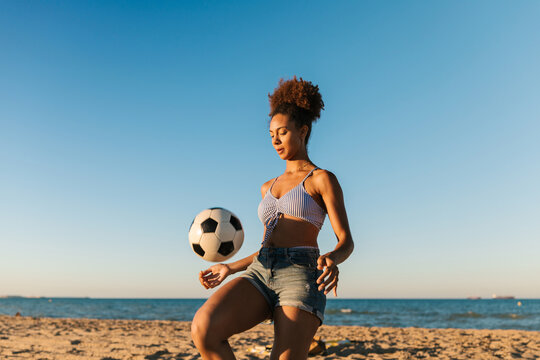 Woman playing with soccer ball on beach