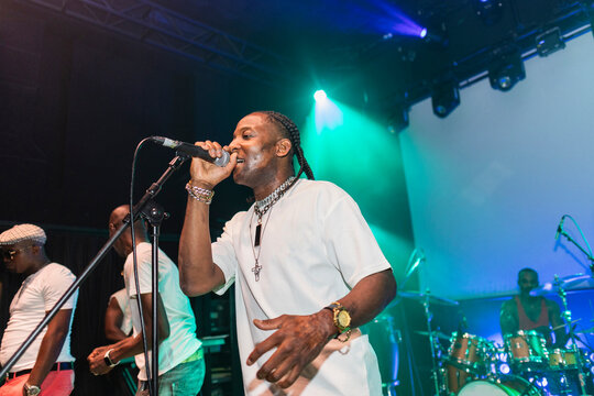 Black male singer performing live on stage with band