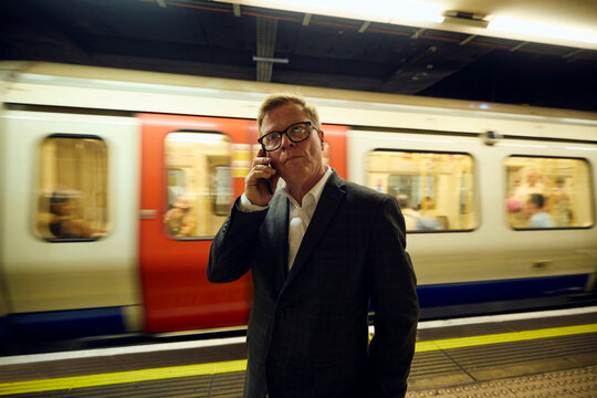 Elegant man talks on the phone at the subway platform