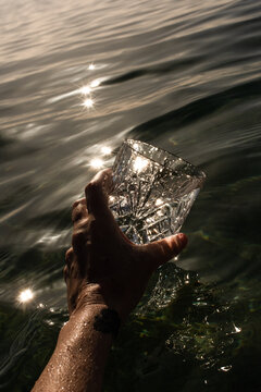A hand holds a glass and fills it with seawater