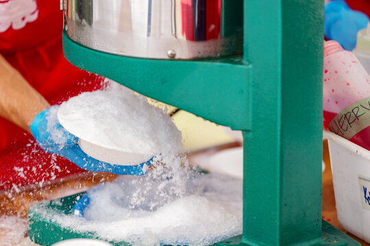Close-up of a kakigori shaved ice machine crushing ice into a bowl at a Japanese summer festival, refreshing dessert treat for hot weather