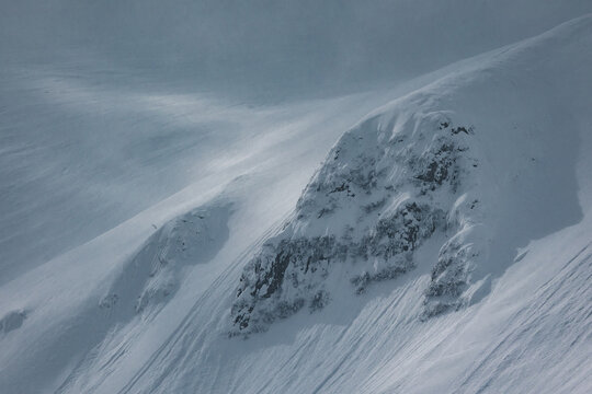 Dramatic snow-covered mountain ridges emerging through clouds 