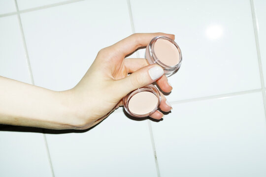 Hand holding nude beige makeup beauty products with flashlight