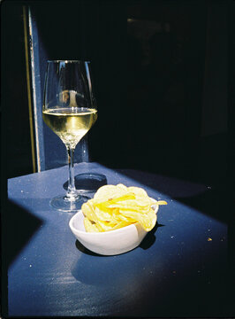 White wine glass and potato chips on table enjoying snacks