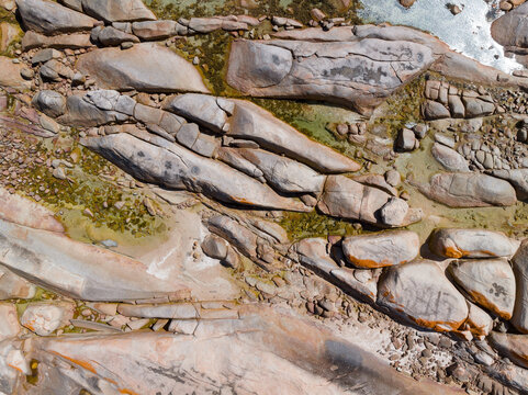 Weathered granite rocks with colored lichen along a rugged coastline