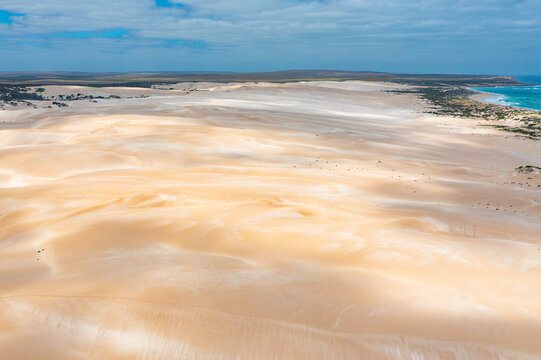 Shadow patterns on coastal sand dunes stretching off to the horizon