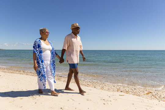 Senior Black Couple walk beach hold hand 