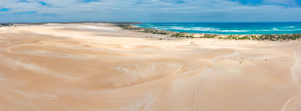 Shadow patterns on coastal sand dunes stretching off to the horizon