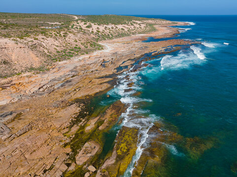 Waves crashing onto rocky reefs along a remote rugged coastline