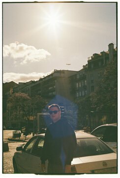 Man Standing in Lisbon Street with Sun Flare and Airplane in Sky