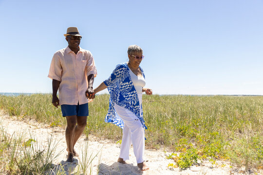 Senior Black Couple walk beach path 