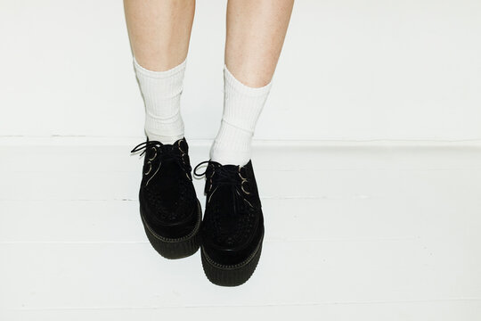 Person wearing black fashion style platform sneakers and white socks