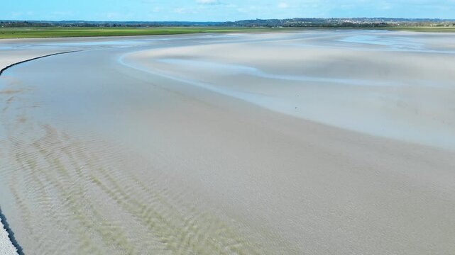Drone view of low tide landscape in Normandy featuring smooth sandbanks, thin water lines and open tidal coastal terrain