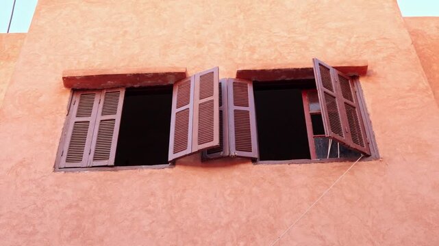 Open Wooden Shutters On Sunlit Peach Stucco Wall Window In Mediterranean Style Building