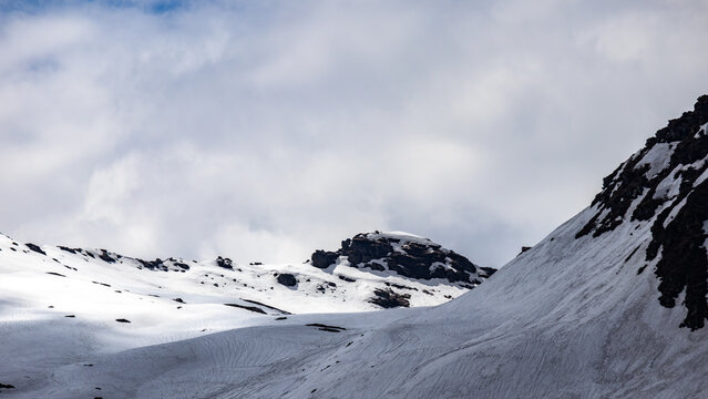 Snow-Covered Himalayan Mountain Pass with Rugged Rocky Peaks Under a Dramatic Cloudy Sky