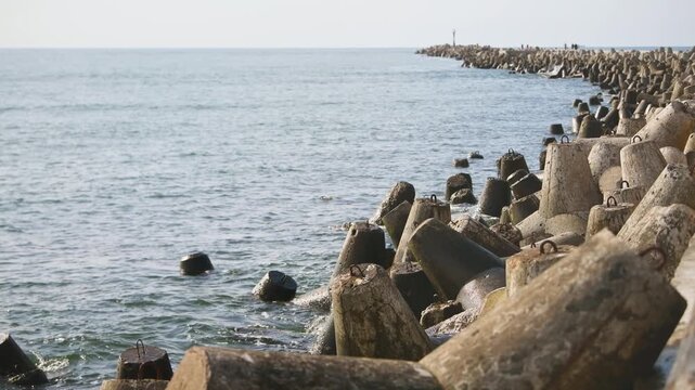 Coastal sea breakwater with concrete wave breakers under soft natural light along calm ocean horizon