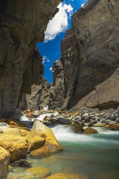 Turquoise Himalayan River Flowing Through a Dramatic Rocky Gorge with Towering Mountain Cliffs