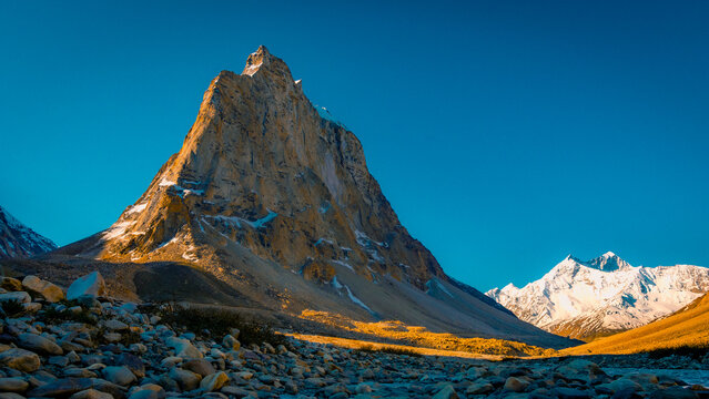 Gonbo Rangjon sacred himalayan mountain peak glowing in golden sunlight in Zanskar Ladakh with snow capped peaks under a clear blue sky