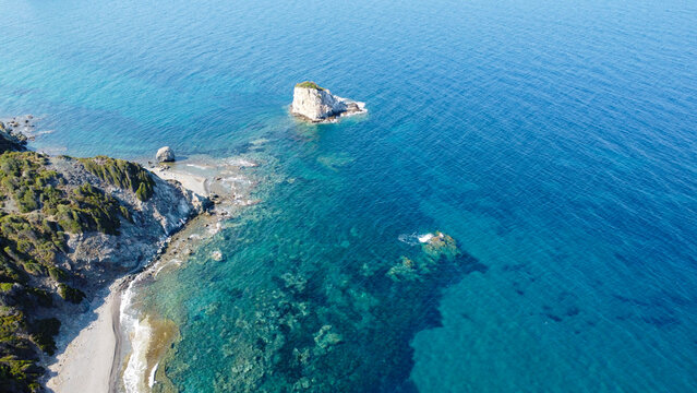 Aerial view of rocky islet in turquoise sea near cliff coast