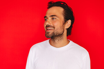 Obraz premium Studio portrait of a handsome young caucasian man with dark hair and beard wearing white long sleeve t shirt smiling with open mouth looking left against vibrant red background commercial project 