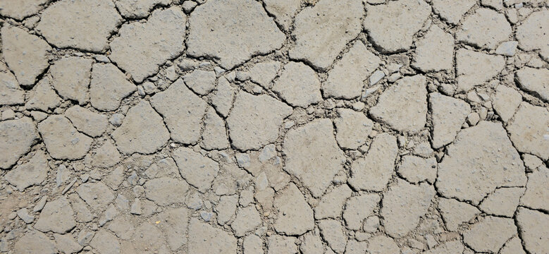 Dusty dry cracked asphalt texture, damaged road pavement abstract background