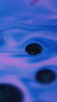 Vertical video. Shimmer ink. Spot fluid. Defocused blue pink colorful water combination round oil chemical texture spreading on abstract background.