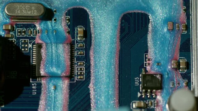 Circuit tech. Flowing glitter dye. Pink blue shimmering paint stream on hardware scheme. Color blur abstract equipment background.