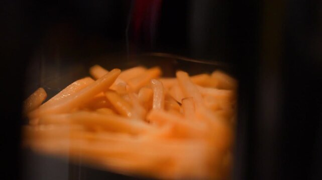 French fries cooking inside an air fryer. Crispy potato snack being prepared in modern kitchen appliance. Healthy fat free fried food culinary process for dining and fast food meal.