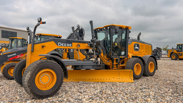 Regina, Canada - July 20, 2026: John Deere 872 motor grader parked on gravel lot with 710 wheel loader visible behind, overcast sky