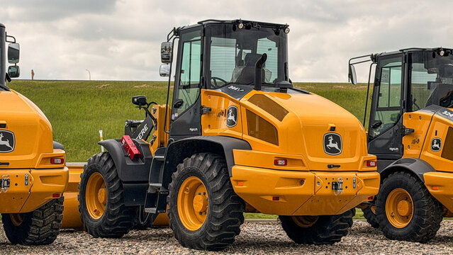 Regina, Canada - July 20, 2026: John Deere 344L HighLift wheel loaders parked on gravel lot with prairie grassland background