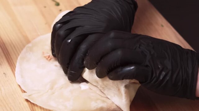 Shawarma rolling. Tortilla wrap. Vegetable fast food. Chef preparing round flatbread with meat sauce vegetable. Hand cooking hot meal.