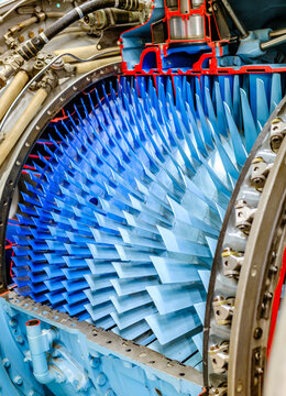 Detailed view of an airplane engine showcasing its complex turbine design and colorful components during a maintenance inspection