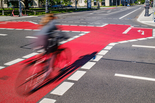 Bicycle lane marking on a street shows direction for cyclists in a busy urban area during the day near shops and parks