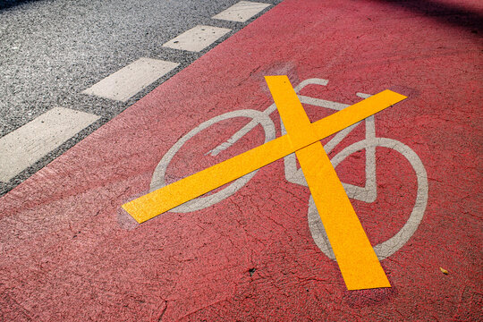 Bicycle lane marking on a street shows direction for cyclists in a busy urban area during the day near shops and parks