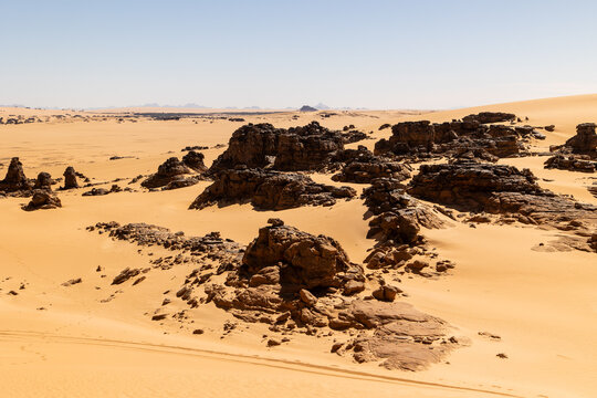 Dark Rock Formations Rising From the Dunes