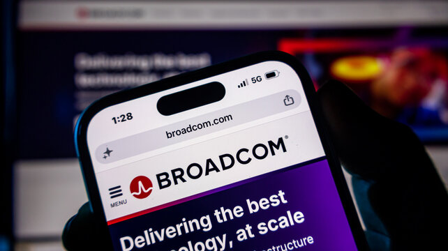 Smartphone displaying broadcom corporate website in dark environment with glowing background.