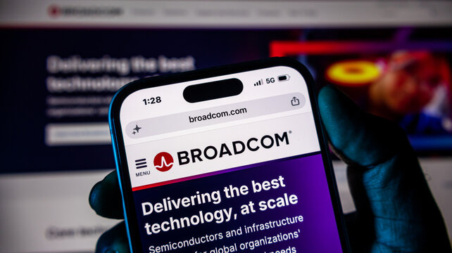 Smartphone displaying broadcom corporate website in dark environment with glowing background.