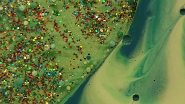 Glitter ink liquid. Oil paint splash. Defocused green blue color water bright sequins bubbles round texture floating on abstract acrylic art background.