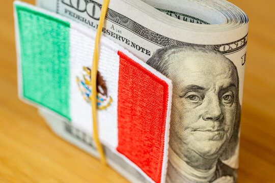US Dollar and Mexican Peso currency exchange concept with Mexico flag patch on top of USD cash stack. Foreign remittances, cross-border trade and Latin American economy