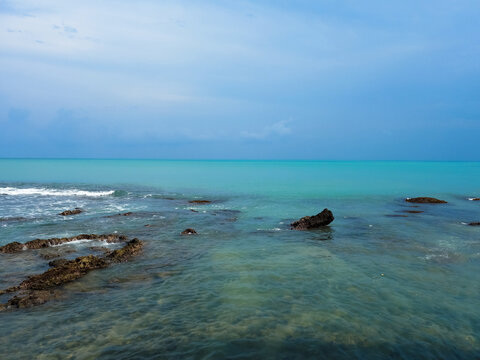 Turquoise tropical sea with rocky shore under dramatic blue sky