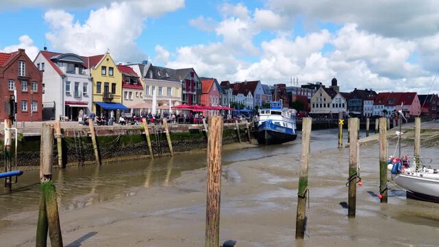 Historic harbor of Husum with an boat during the incoming tide, surrounded by the colorful old town and North Sea tidal waters.