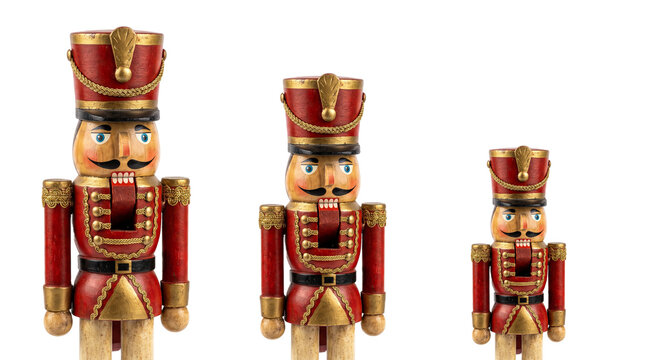 Three traditional wooden nutcracker soldier figurines of varying sizes arranged in a row isolated on transparent background