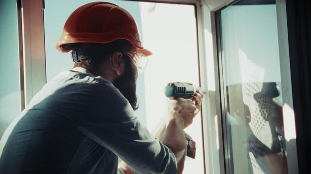Worker Installing Plastic Window Frame Using Cordless Screwdriver. Repairing Glass Unit. Home Improvement Handyman Maintenance Service