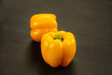 Two yellow bell peppers on dark textured background © Andrei Starostin