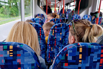 Interior perspective from behind passengers riding on a public bus or train with patterned seats. © Констянтин Батыльчук